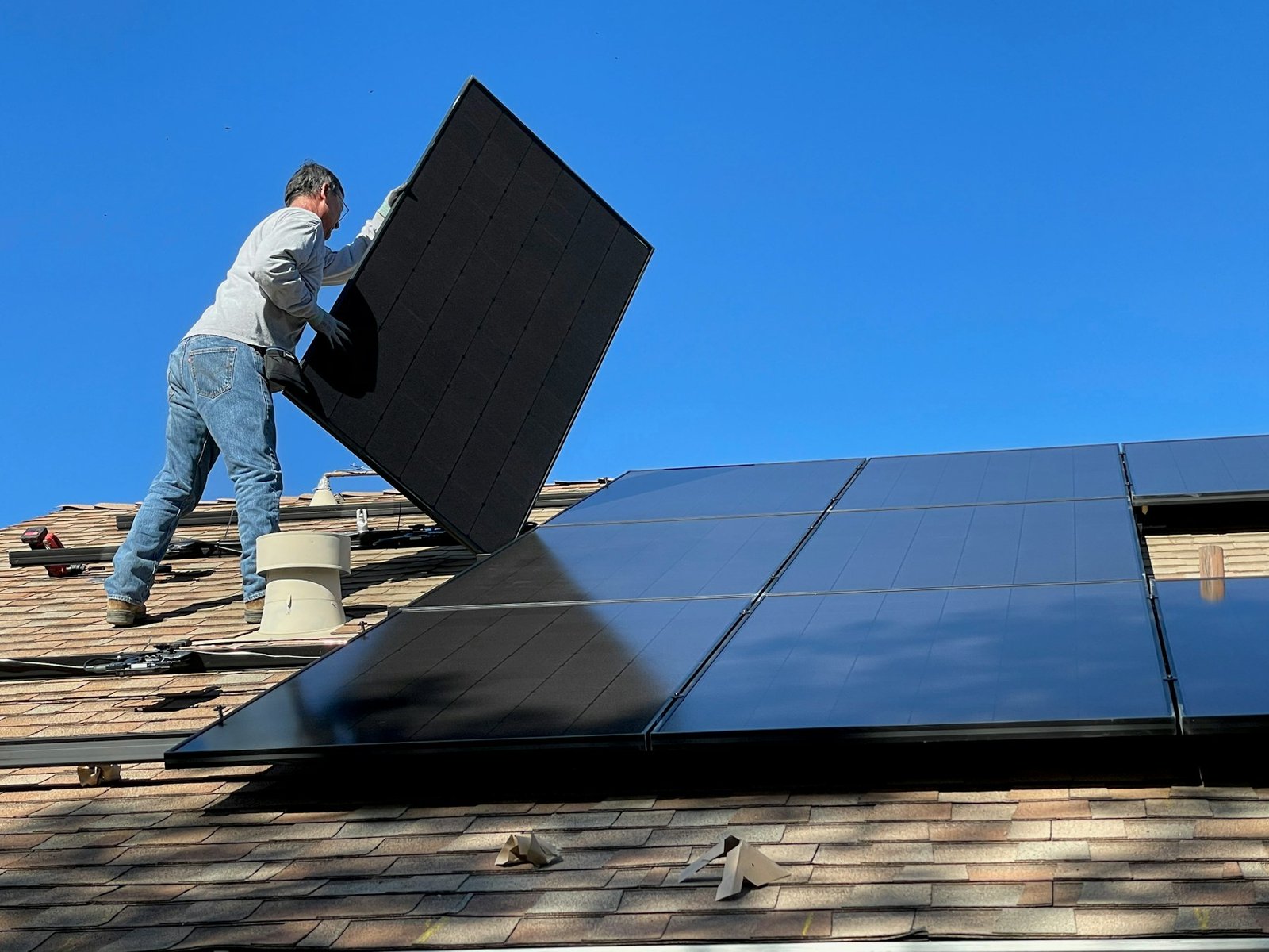Fachkraft montiert ein Photovoltaikmodul auf einem Dach